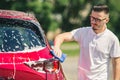 Car detailing - the man holds the microfiber in hand and polishes the car. Man worker washing car`s alloy wheels on a car wash. Royalty Free Stock Photo