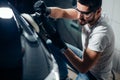 Car detailing - man with orbital polisher in auto repair shop. Selective focus. Royalty Free Stock Photo