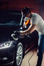 Car detailing - man with orbital polisher in auto repair shop. Selective focus.