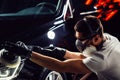 Car detailing - man with orbital polisher in auto repair shop. Selective focus. Royalty Free Stock Photo