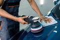 Car detailing and polishing concept. Hands of professional African man worker, with orbital polisher, polishing blue