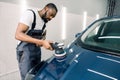 Car detailing and polishing concept. Professional African male car service worker, holding in hands orbital polisher Royalty Free Stock Photo