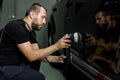 Car detailing and polishing concept. Professional Caucasian male car service worker, wearing black uniform, holding in Royalty Free Stock Photo