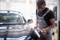 Car detailing and polishing concept. young professional car service male worker with orbital polisher Royalty Free Stock Photo