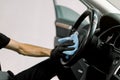 Car detailing series, car wash and cleaning concept. Cropped close up image of hand of male worker in black protective