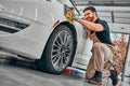 Car detailing series. Worker cleaning white car