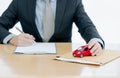 A Car on document envelope with man signing purchase documents in background. while hand complete the insurance policy, rental