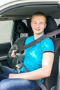 Car driver. Caucasian teen boy fastening seat belt in the car.