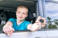 Car driver. Caucasian teen boy showing car key in the new car.