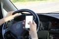 Car driver presses the blank screen of smartphone with his thumb while driving along the road. Copy space in display frame Royalty Free Stock Photo