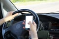 Car driver presses the blank screen of smartphone with his thumb while driving along the road. Copy space in display frame