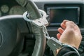 Car driver hand handcuffed to steering wheel, arrest, driving ban by traffic violator Royalty Free Stock Photo