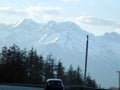 A car drives along the freeway against the background of snow-capped mountains and power lines