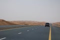 A car drives on an empty road in the deserts of Dubai, UAE Royalty Free Stock Photo