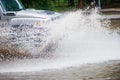 The car drives quickly through a puddle, splashes fly from under the wheels. Much water. High speed. Royalty Free Stock Photo