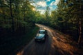Car driving along winding forest road in autumn light. Royalty Free Stock Photo
