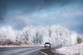 Car driving on asphalt road in winter mountains with frost-covered trees Royalty Free Stock Photo