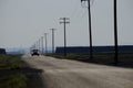 Car Driving Down Country Road Headlights Power Lines and Poles