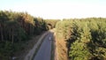 car driving on an empty road in a wooded area, aerial view, top down view, filmed in motion