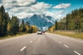 Car driving on highway to rocky mountains in autumn forest at national park Royalty Free Stock Photo