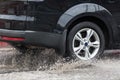 Car driving through a puddle on a flooded road with water and splashes caused by heavy rain. Royalty Free Stock Photo