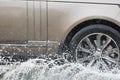 Car driving through a puddle on a flooded road with water and splashes caused by heavy rain. Royalty Free Stock Photo