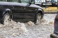 The car is driving through a puddle in heavy rain. Splashes of water from under the wheels of a car. Flooding and high water in Royalty Free Stock Photo