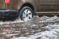 The car is driving through a puddle in heavy rain. Splashes of water from under the wheels of a car. Flooding and high water in Royalty Free Stock Photo