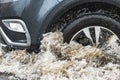 The car is driving through a puddle in heavy rain. Splashes of water from under the wheels of a car. Flooding and high water in Royalty Free Stock Photo