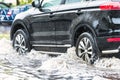 The car is driving through a puddle in heavy rain. Splashes of water from under the wheels of a car. Flooding and high water in Royalty Free Stock Photo