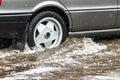 The car is driving through a puddle in heavy rain. Splashes of water from under the wheels of a car. Flooding and high water in Royalty Free Stock Photo