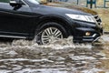 The car is driving through a puddle in heavy rain. Splashes of water from under the wheels of a car. Flooding and high water in Royalty Free Stock Photo