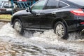 The car is driving through a puddle in heavy rain. Splashes of water from under the wheels of a car. Flooding and high water in Royalty Free Stock Photo