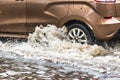 The car is driving through a puddle in heavy rain. Splashes of water from under the wheels of a car. Flooding and high water in Royalty Free Stock Photo