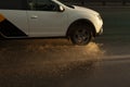 The car is driving in a puddle. Splashes of water from the wheels of the car. Transport on the highway