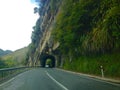 Car driving on road into tunnel carved out rock of mountain