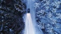 Car driving on snowy country road through winter forest at night. High beam on. .