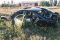 Car dump, scrap metal. Close-up of an old abandoned car in a junkyard with grass sprouting inside and overgrown cobwebs