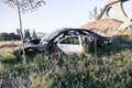 Car dump, scrap metal. Close-up of an old abandoned car in a junkyard with grass sprouting inside and overgrown cobwebs