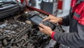 The car engine being diagnosed with a digital tablet by a mechanic Royalty Free Stock Photo