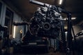Car engine suspended on a hydraulic hoist in the workshop Royalty Free Stock Photo
