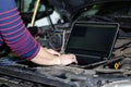 Car expert using laptop for auto diagnostics.