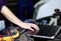 Car expert using laptop for auto diagnostics.