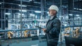 Car Factory Office: Portrait of Male Engineer Wearing Hard Hat Walking, Monitoring Production Royalty Free Stock Photo