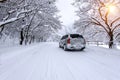 Car and falling snow in winter on forest road with much snow. Royalty Free Stock Photo