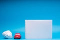 A car figurine between a notebook and a crumbled sheet of paper, on blue background Royalty Free Stock Photo