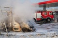 Car fire at the gas station. Burning van and firefighters extinguishing a fire