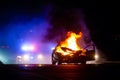 Car on fire at night with police lights in background Royalty Free Stock Photo