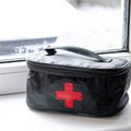 Car first aid kit with a set of medicines to save the life of the driver and passengers stands on a window sill