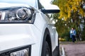 Car front view close-up on the background of a Park alley. Headlight glass. Background design. Detail of modern car headlights Royalty Free Stock Photo